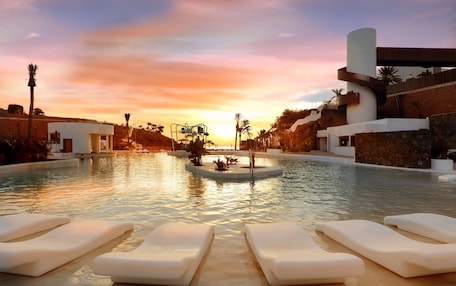 A pool area with lounge chairs, a water feature, and modern architecture.