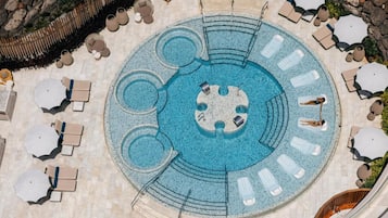 Relax by the pool surrounded by lounge chairs and umbrellas, with a central island and seating areas.