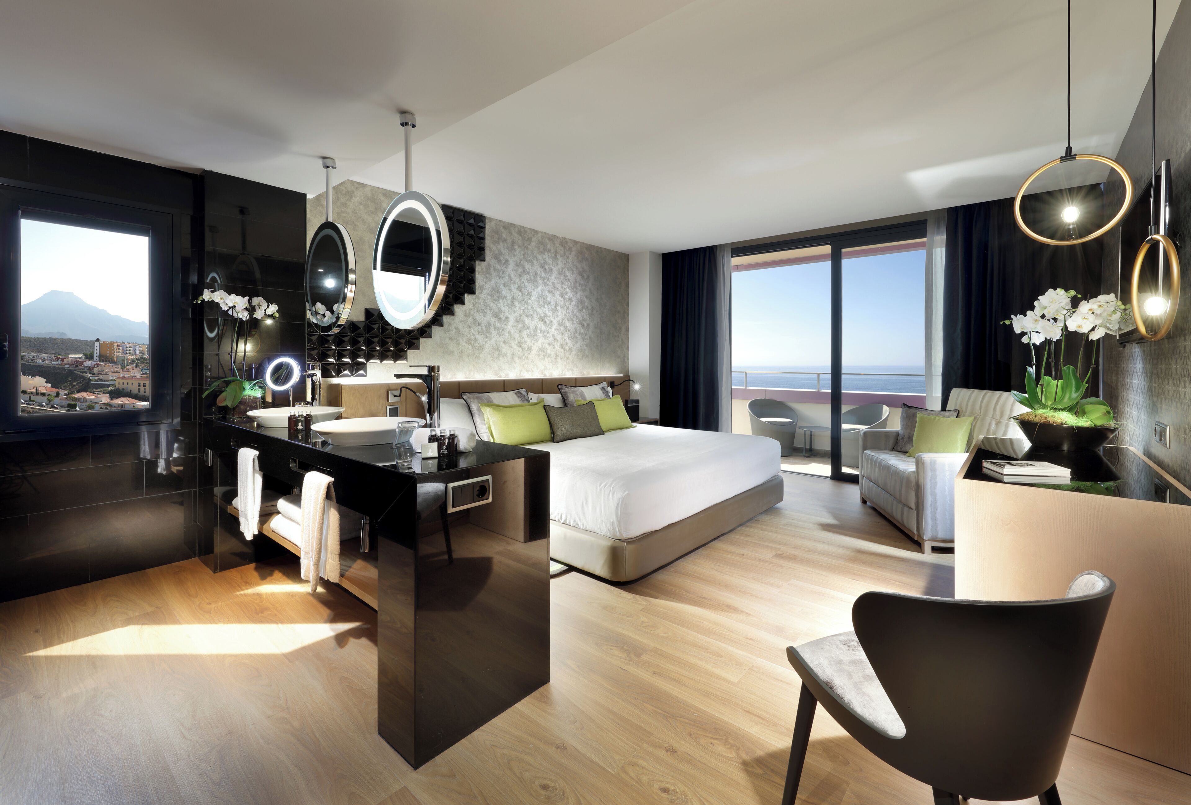 Habitación de hotel moderna con cama, escritorio y baño, que ofrece vistas a la ciudad.