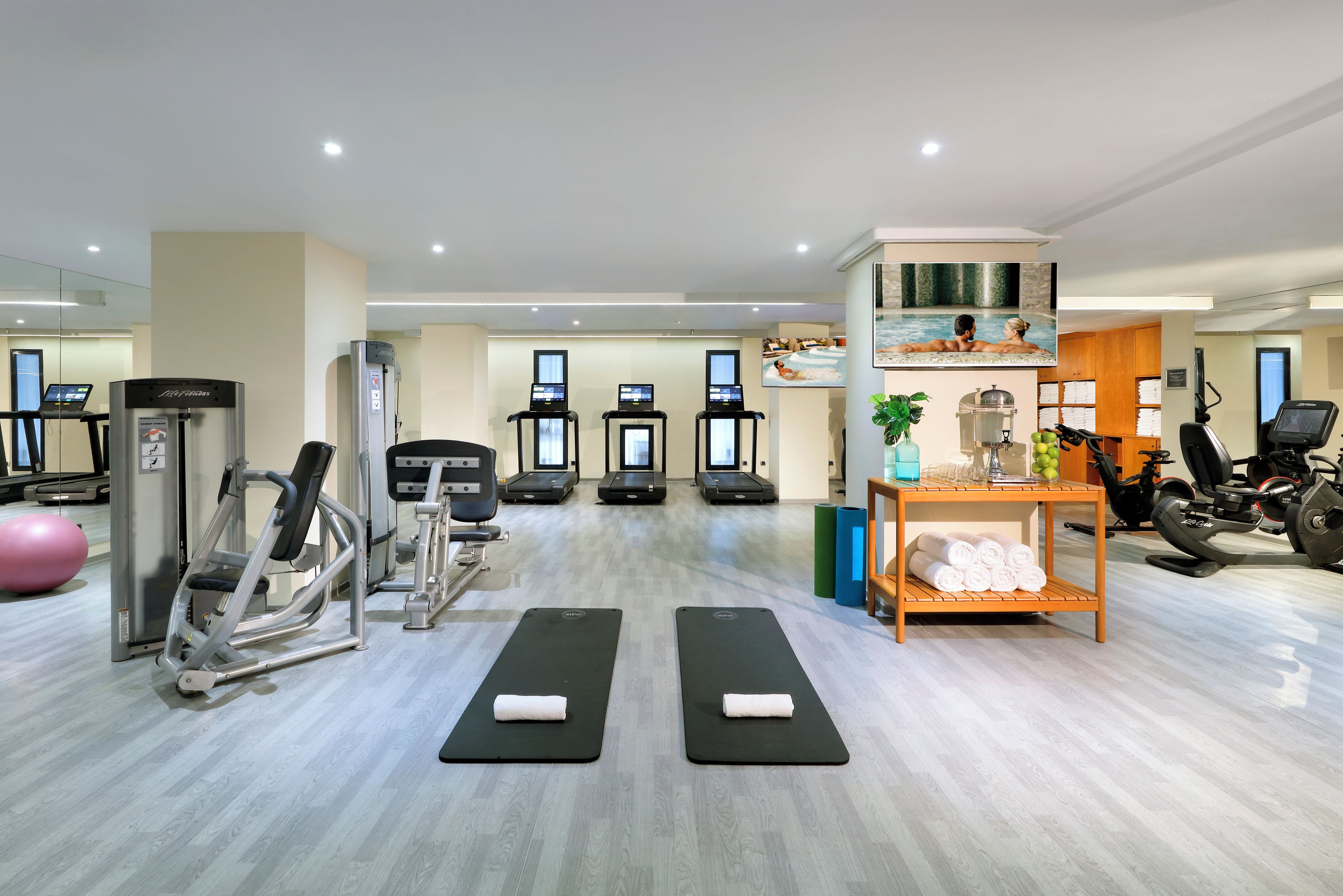 A gym with treadmills, weight machines, and exercise mats.