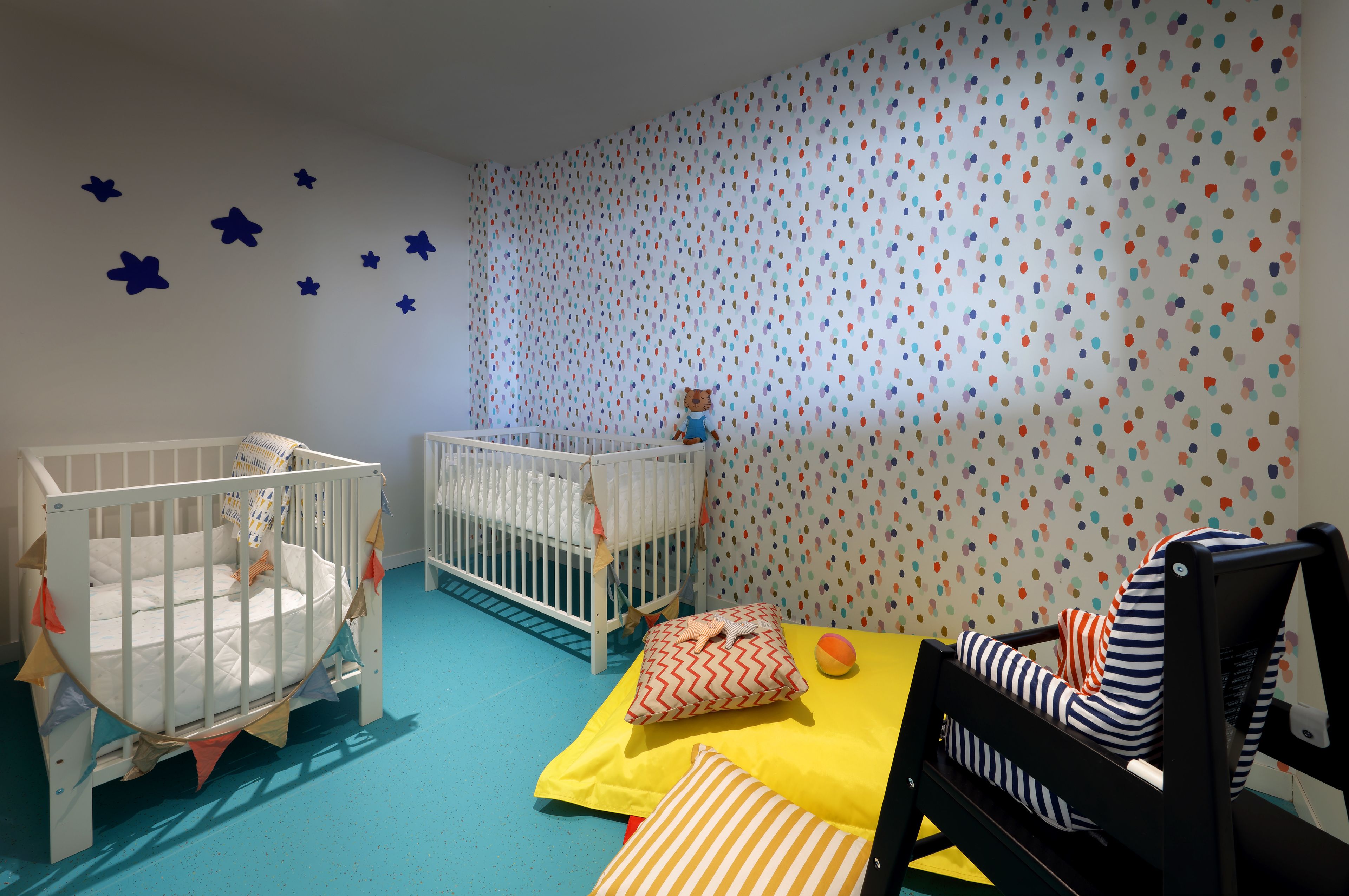Une chambre pour bébé avec deux berceaux, une table à langer et un espace de jeu.