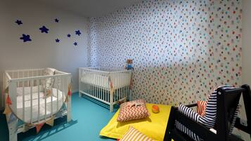 Une chambre pour bébé avec deux berceaux, une table à langer et un espace de jeu.