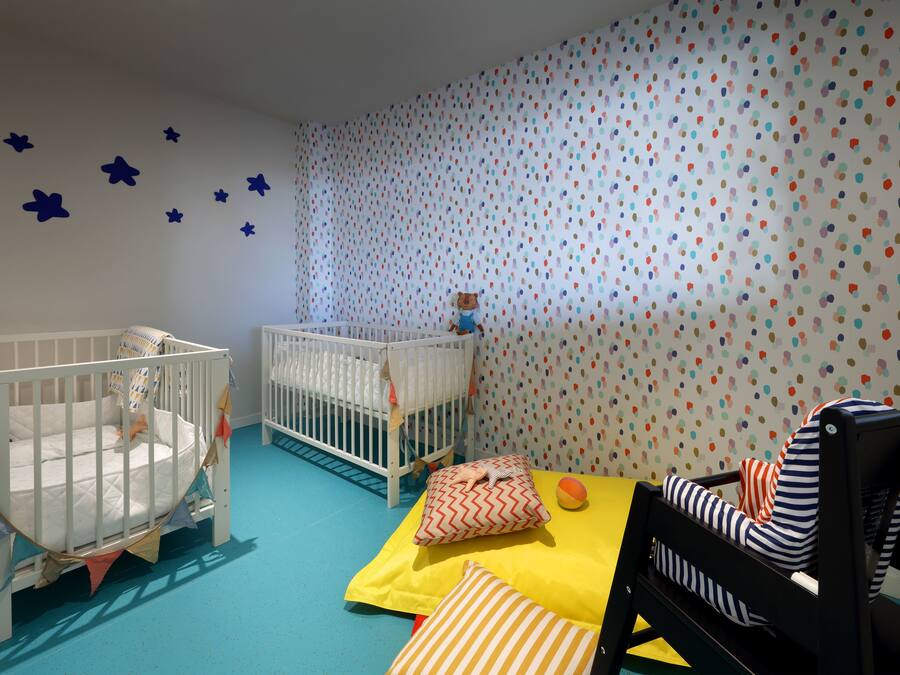 Une chambre pour bébé avec deux berceaux, une table à langer et un espace de jeu.