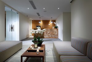 Un moderno vestíbulo de hotel con mostrador de recepción, zona de estar y un arreglo floral decorativo.