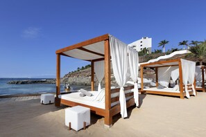 Am Strand, schwarzer Sandstrand, LiegestĂŒhle, Sonnenschirme