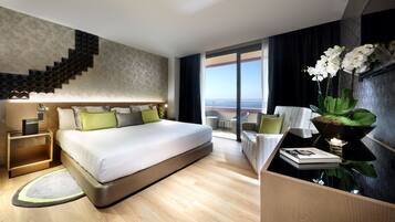 A modern hotel room with a large bed, a staircase, a balcony with a view, and a small table with a plant.