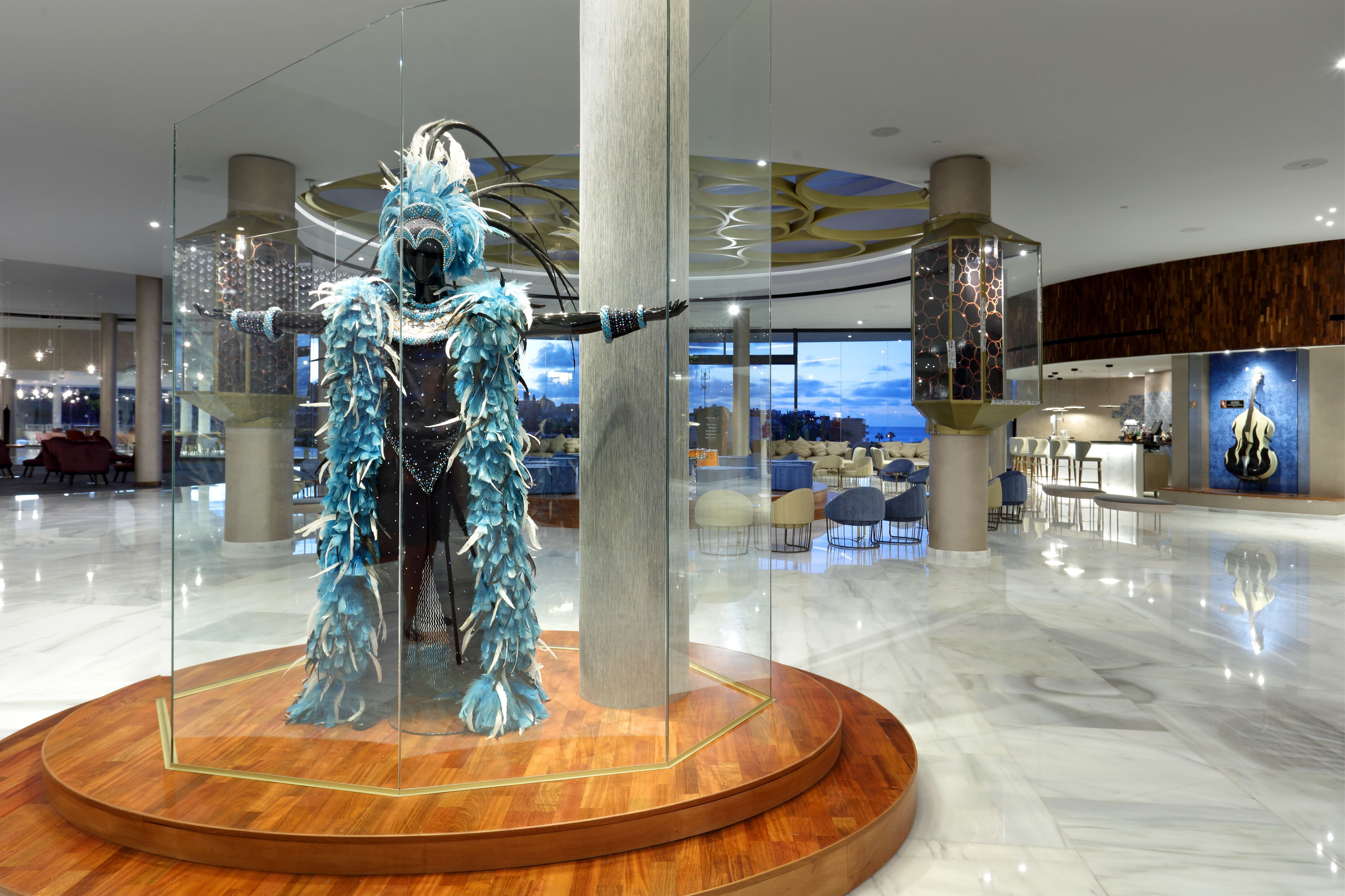 Un moderno vestíbulo de hotel con una vitrina de vidrio que contiene una escultura de plumas azules.