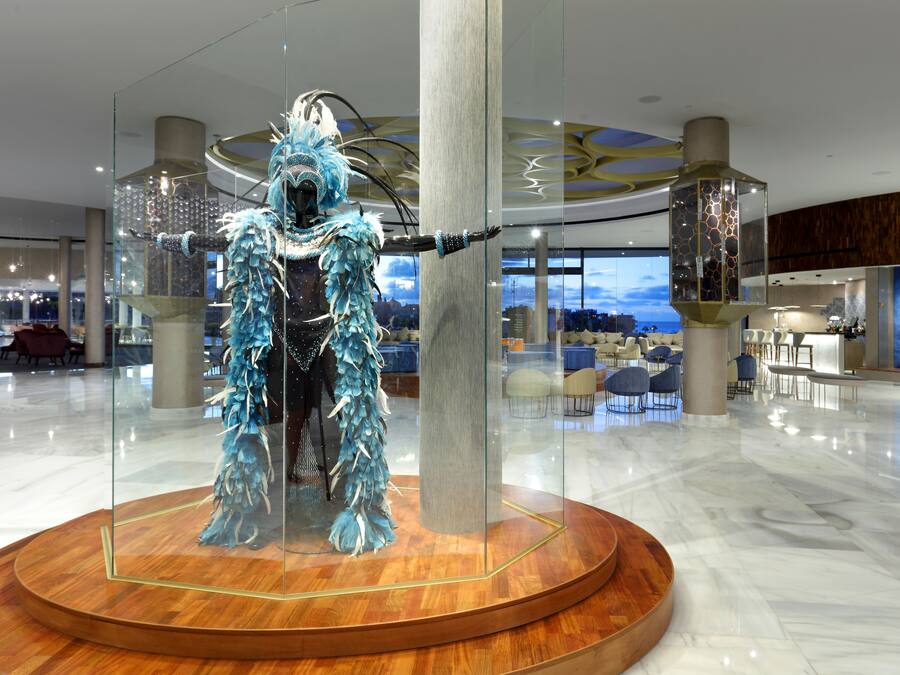Un hall d’hôtel moderne avec une vitrine en verre contenant une sculpture bleue ornée de plumes.