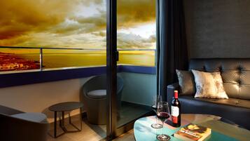 Una habitación moderna con una mesa de vidrio, un sofá y vistas a un atardecer sobre el mar.