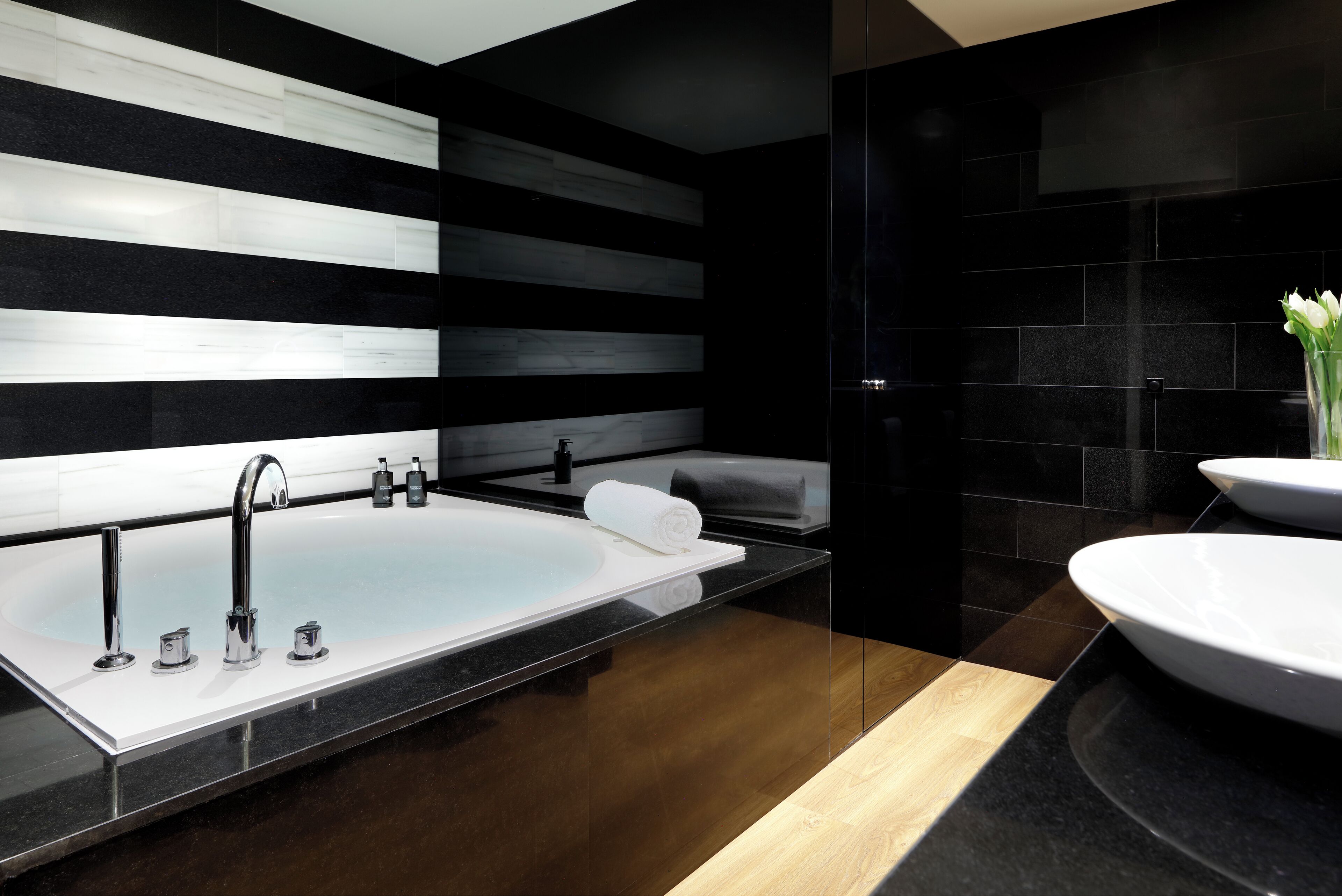 A modern bathroom with a large bathtub, a separate sink, and a vanity with a mirror.