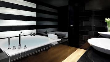 A modern bathroom with a large bathtub, a separate sink, and a vanity with a mirror.