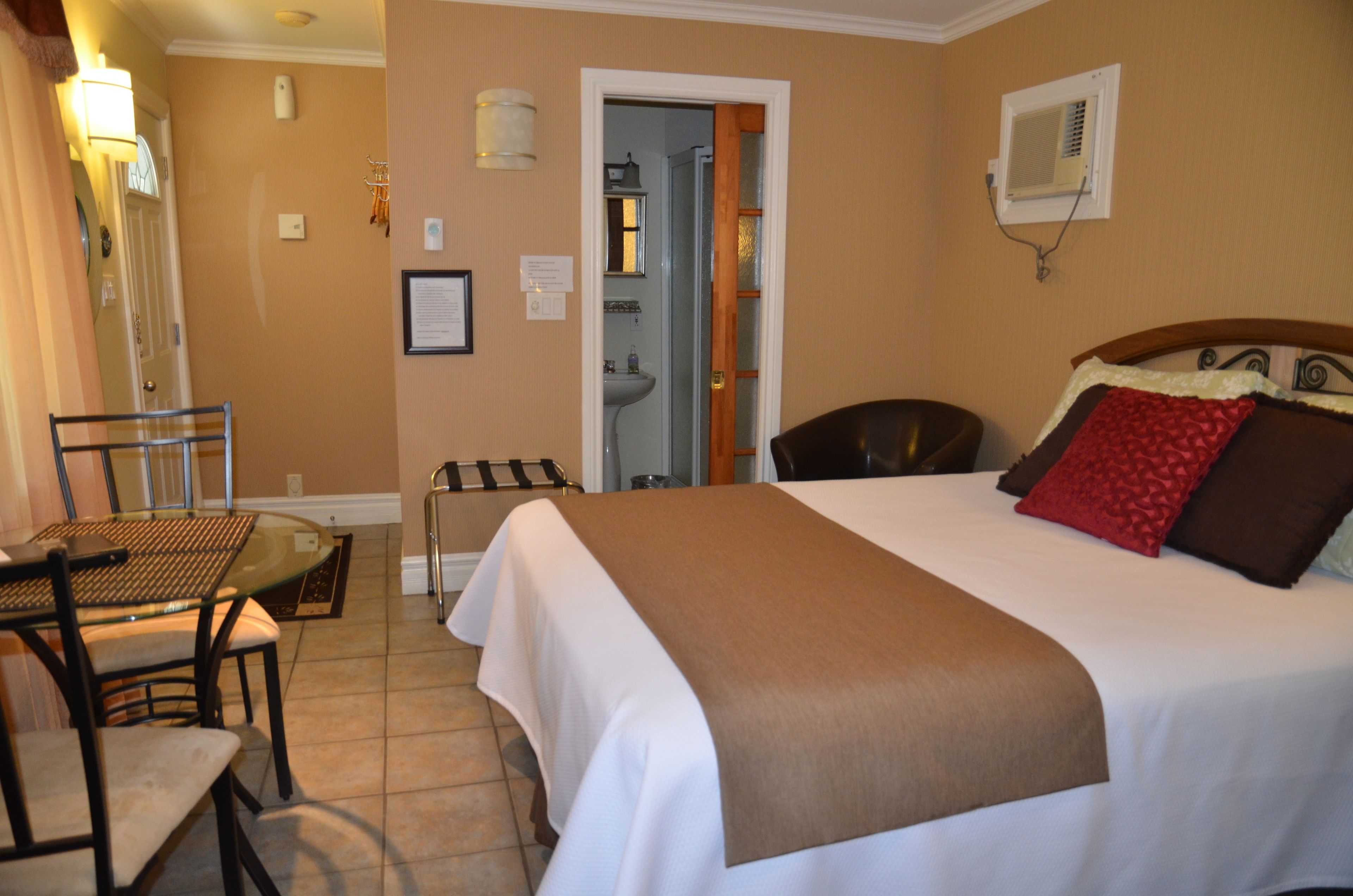 Habitación de hotel con cama, escritorio y silla. Se ve un baño por una puerta abierta.