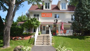 A two-story motel with a front entrance, steps leading up to the door, and a signboard. - Motel Derfal (Repentigny)