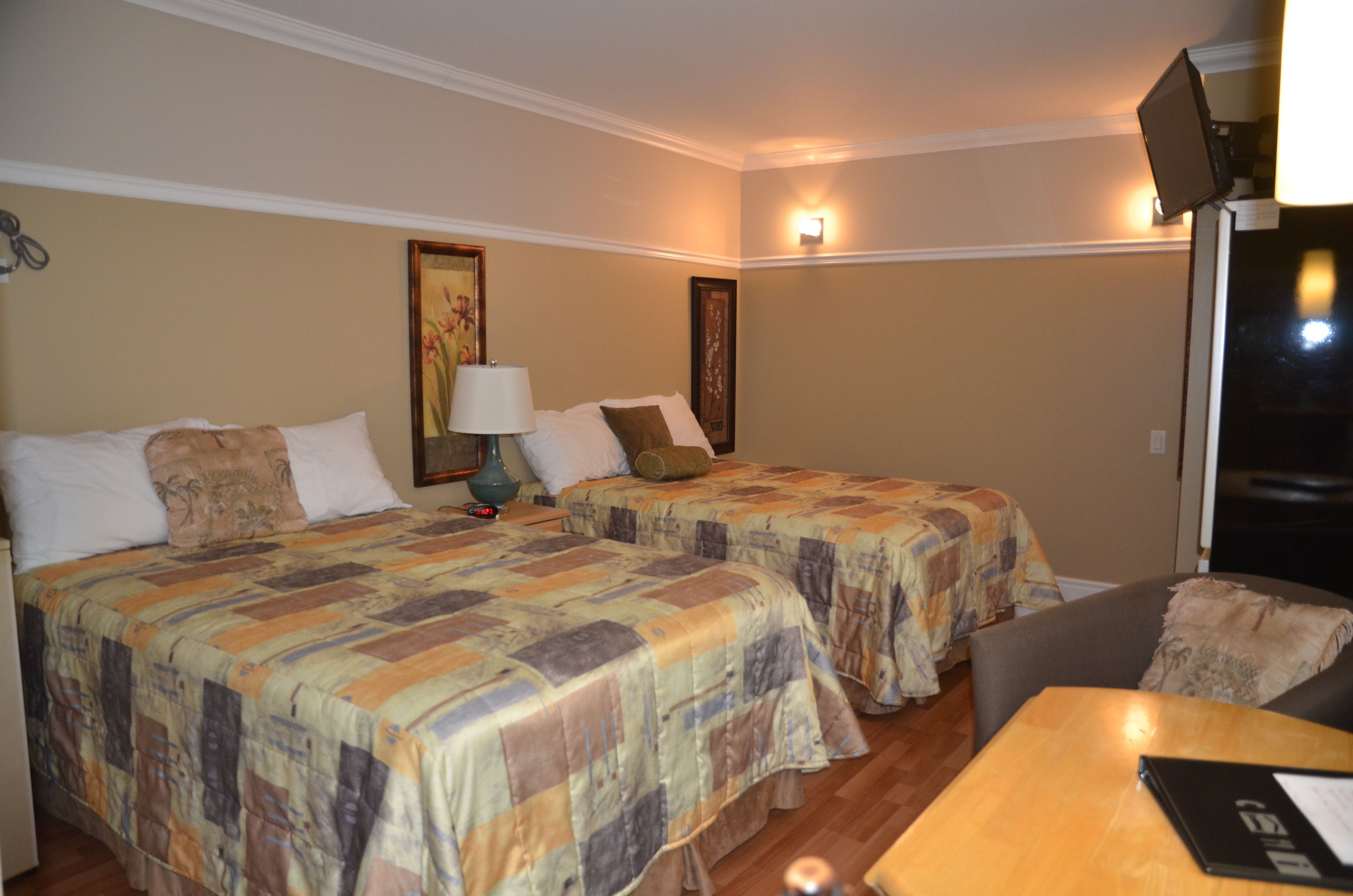 Una habitación de hotel con dos camas, una mesa de madera, una silla y un televisor.