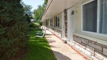 Una hilera de habitaciones de motel con fachada de piedra, un pasillo cubierto y un césped bien cuidado.