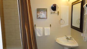 Un baño con cortina de ducha, lavabo, espejo y dos toallas colgadas de ganchos.