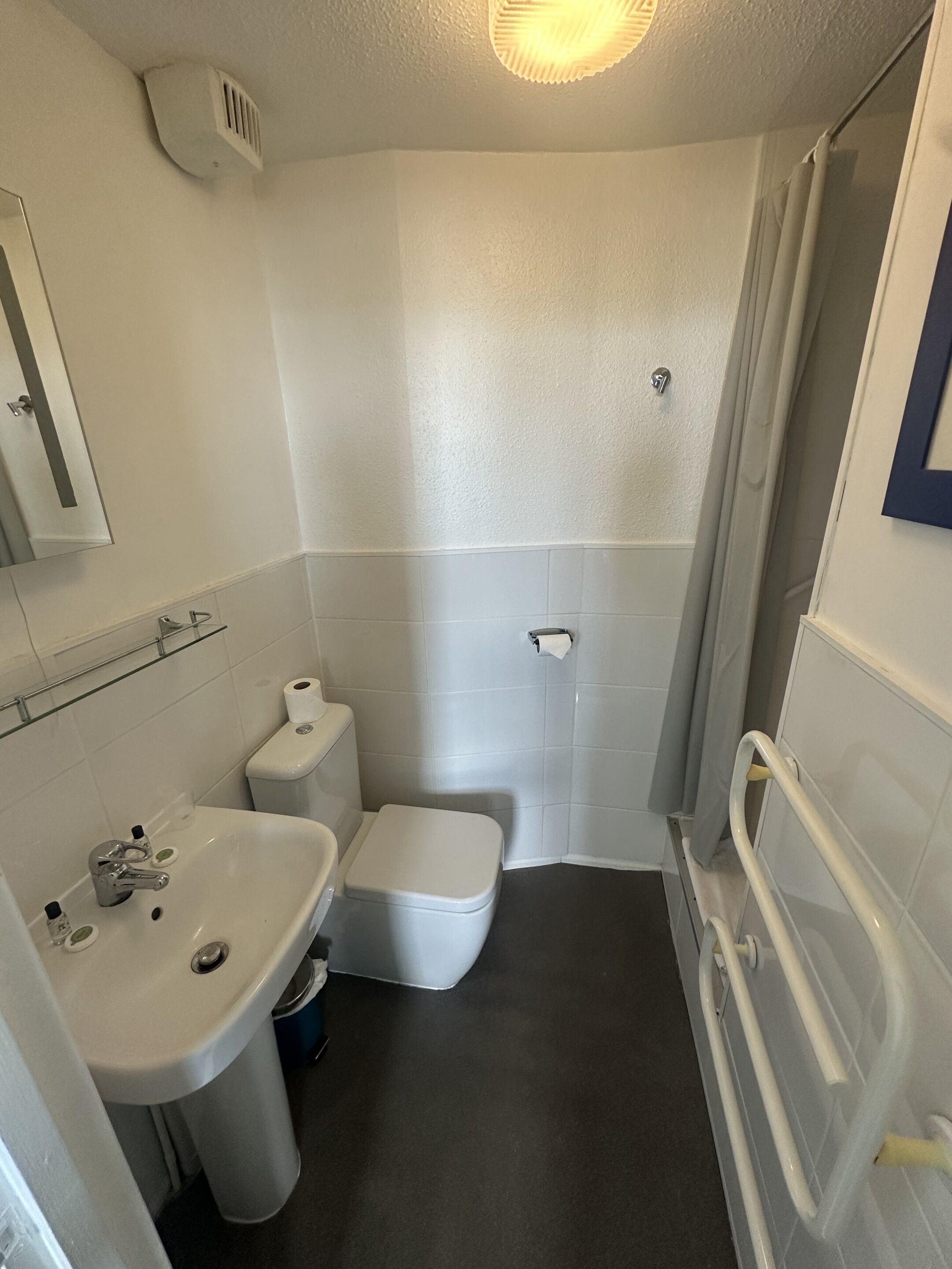 Un baño pequeño y funcional con inodoro, lavamanos y zona de ducha.