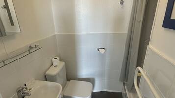 Un baño pequeño y funcional con inodoro, lavamanos y zona de ducha.