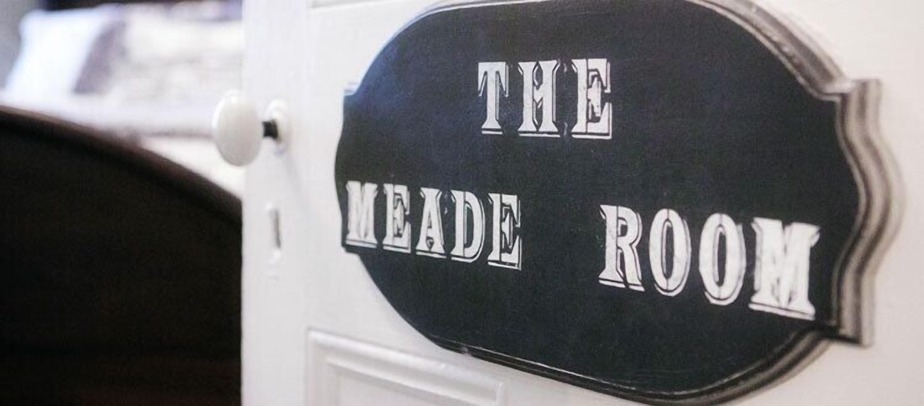 Une enseigne avec l’inscription « THE MEADE ROOM » sur une porte blanche.