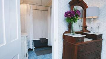 A bathroom with a wooden vanity, a mirror, a vase with flowers, and a shower curtain.