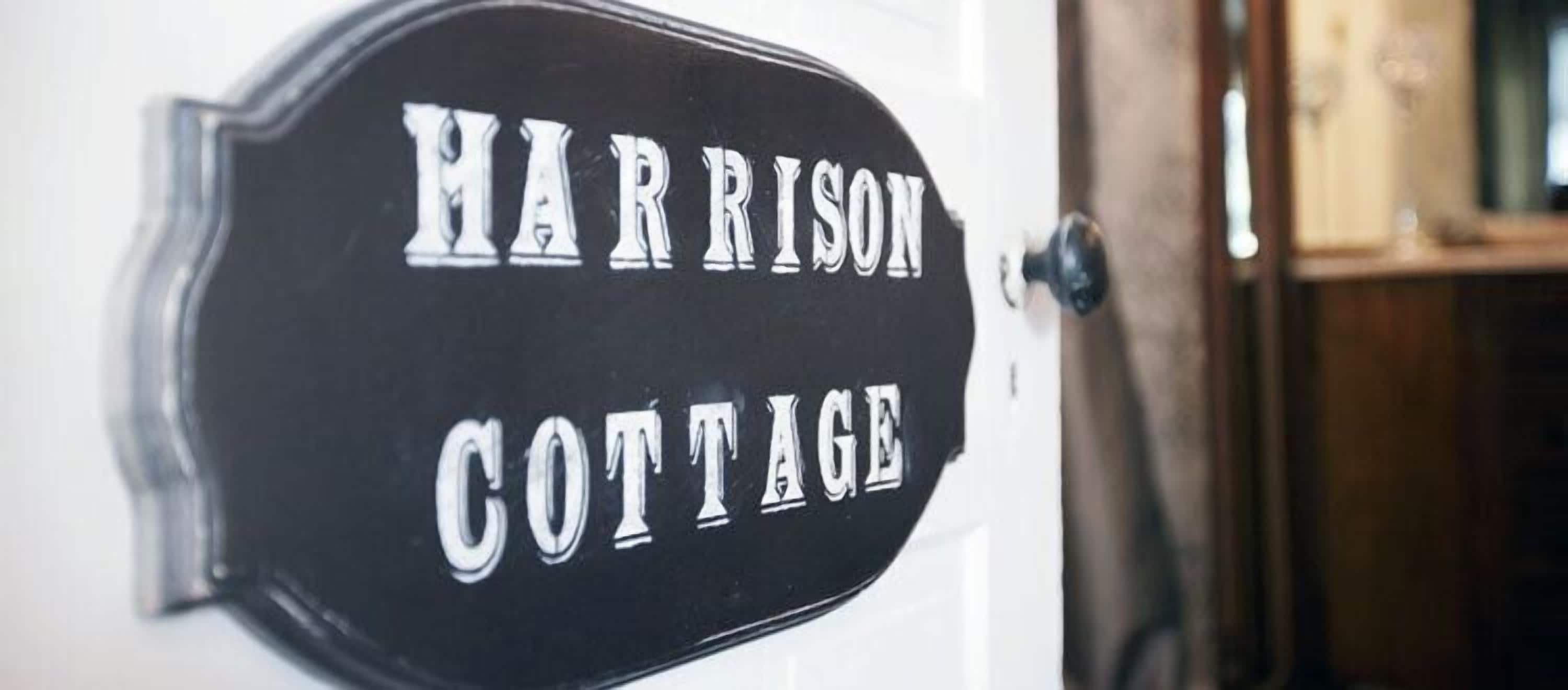 Une plaque noire avec des lettres blanches indiquant : « Harrison Cottage ».