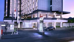 Un hotel moderno con varios pisos, una entrada destacada y un área de estacionamiento.