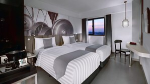 Una habitación de hotel moderna con dos camas, un escritorio, una silla y vistas al atardecer.