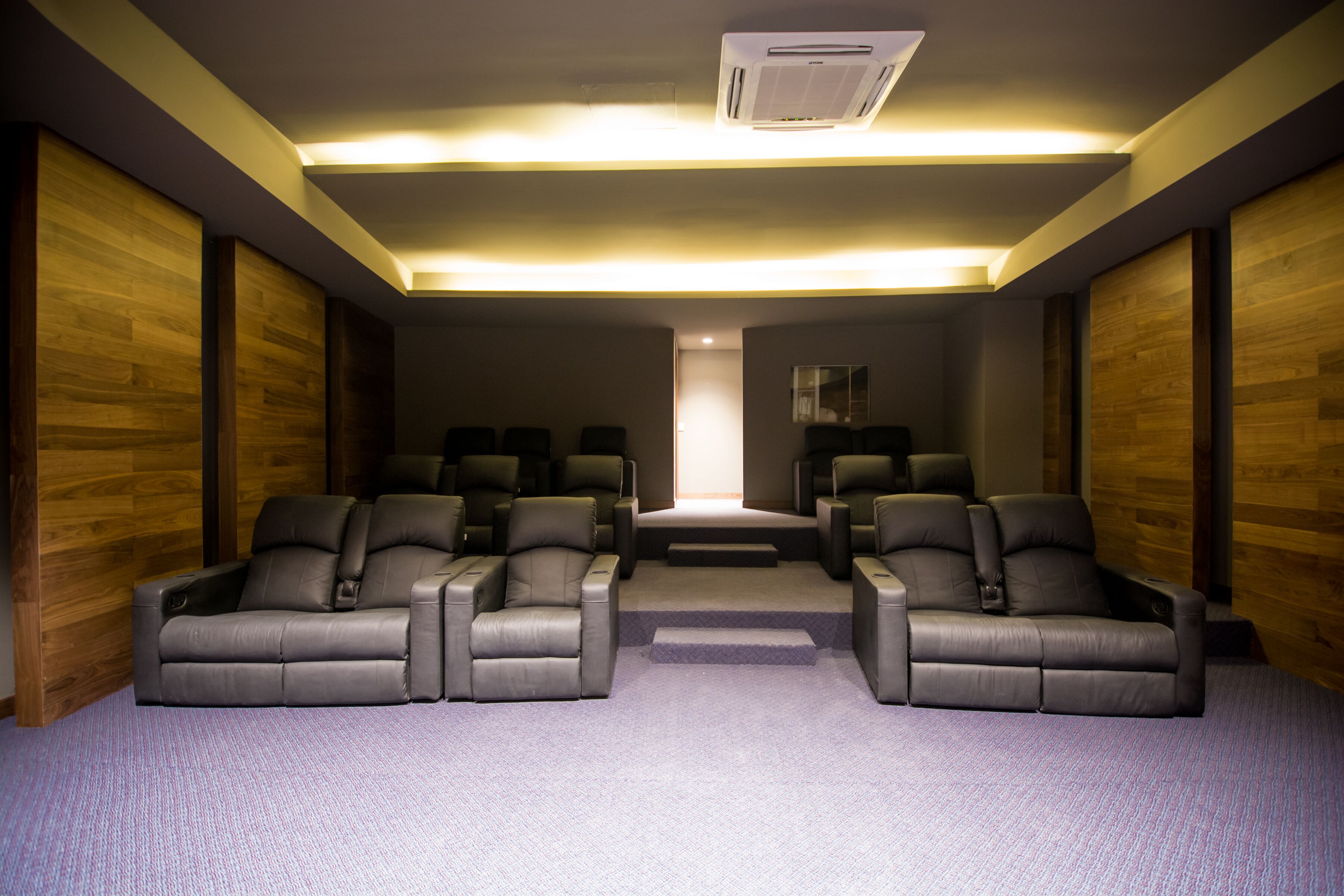 A home theater room with a central seating area and a small stage.