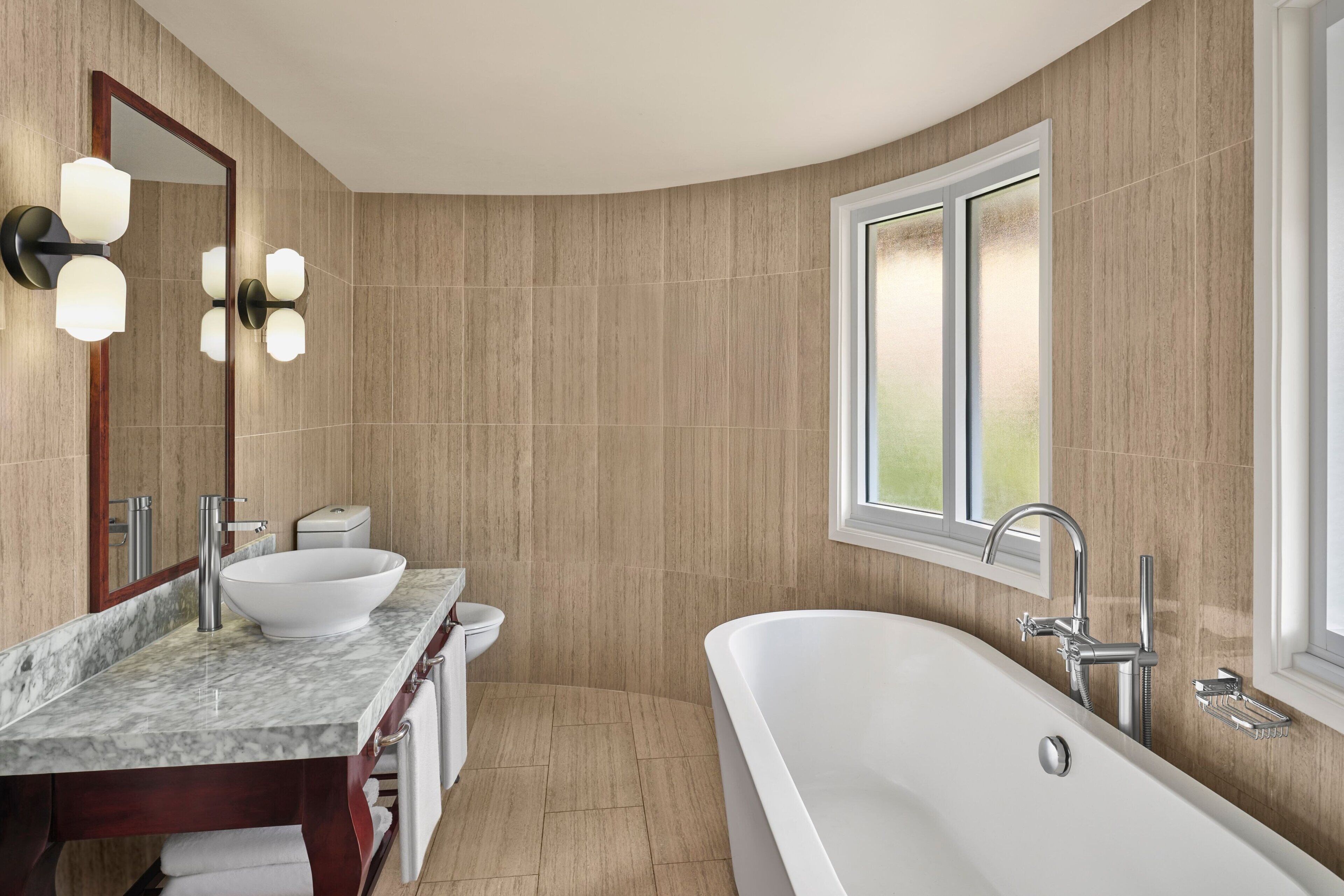 Un baño moderno con una bañera grande, un lavamanos doble y un espejo amplio.