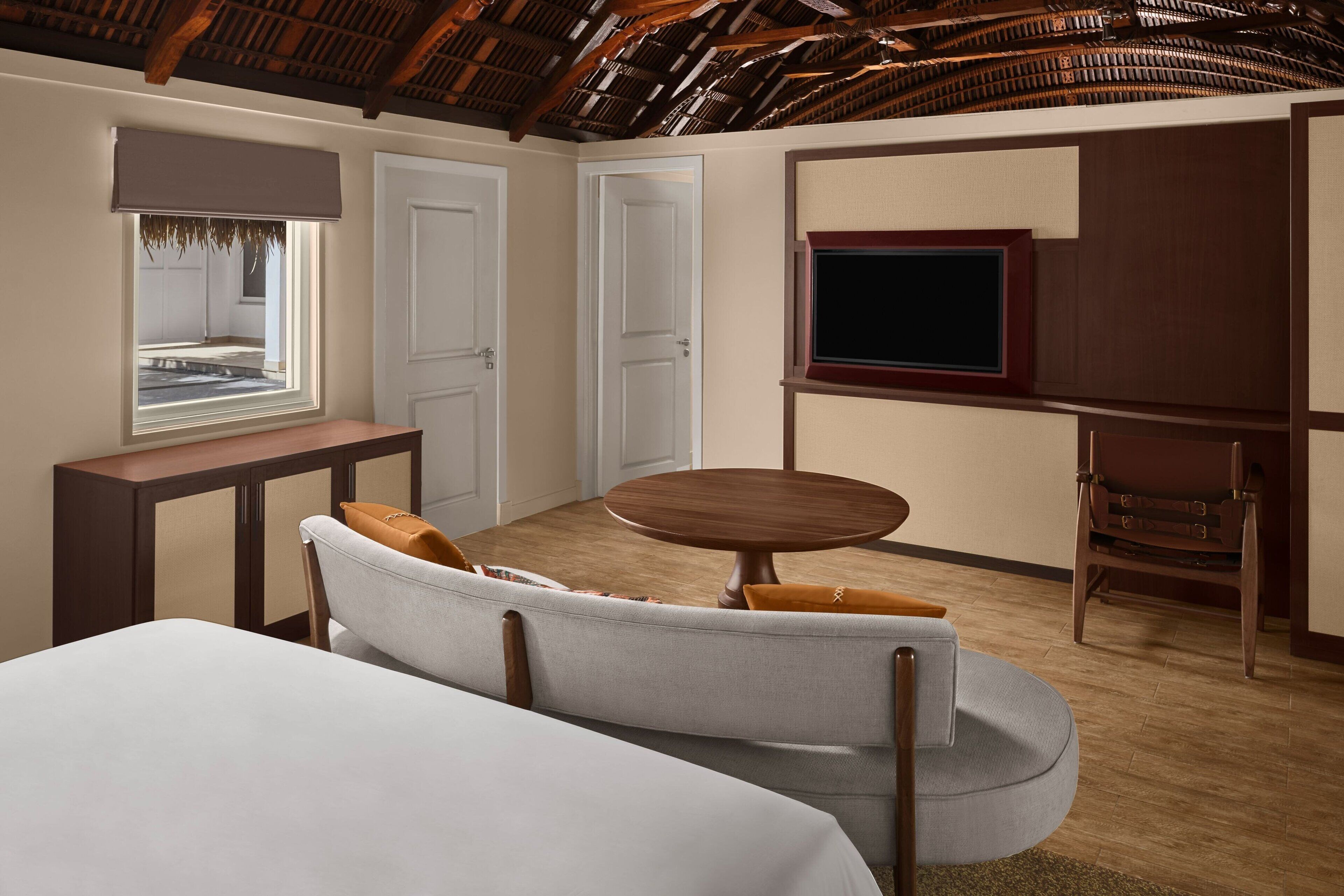 Una habitación con una cama, un sofá, una mesa redonda, un televisor y una ventana.