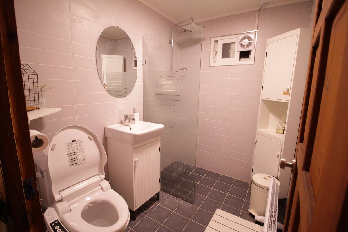A modern bathroom with a toilet, sink, shower, and a mirror.