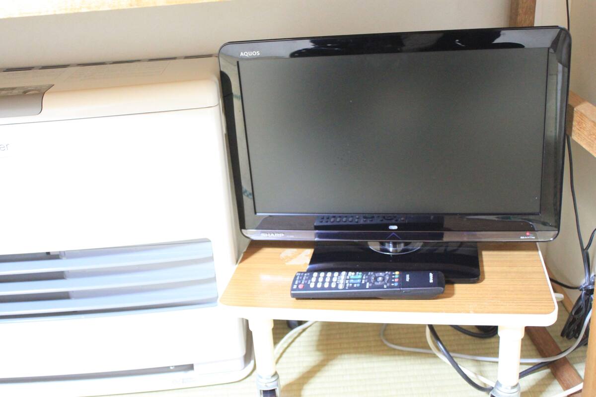 A television on a wooden stand with a remote control.