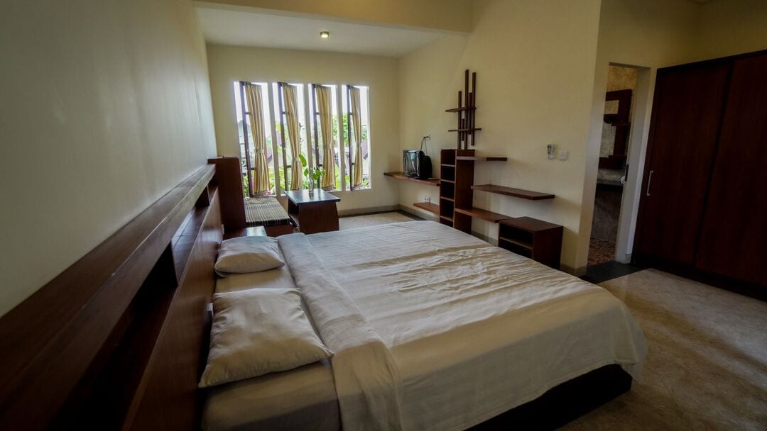Un dormitorio con una cama grande, un banco de madera, un televisor y un armario.