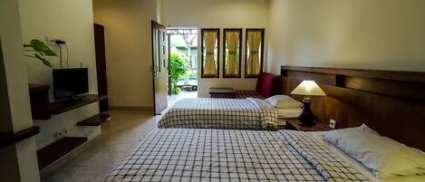 Quarto de hotel com duas camas, uma televisão, uma mesa de cabeceira, um abajur e vista para o exterior.