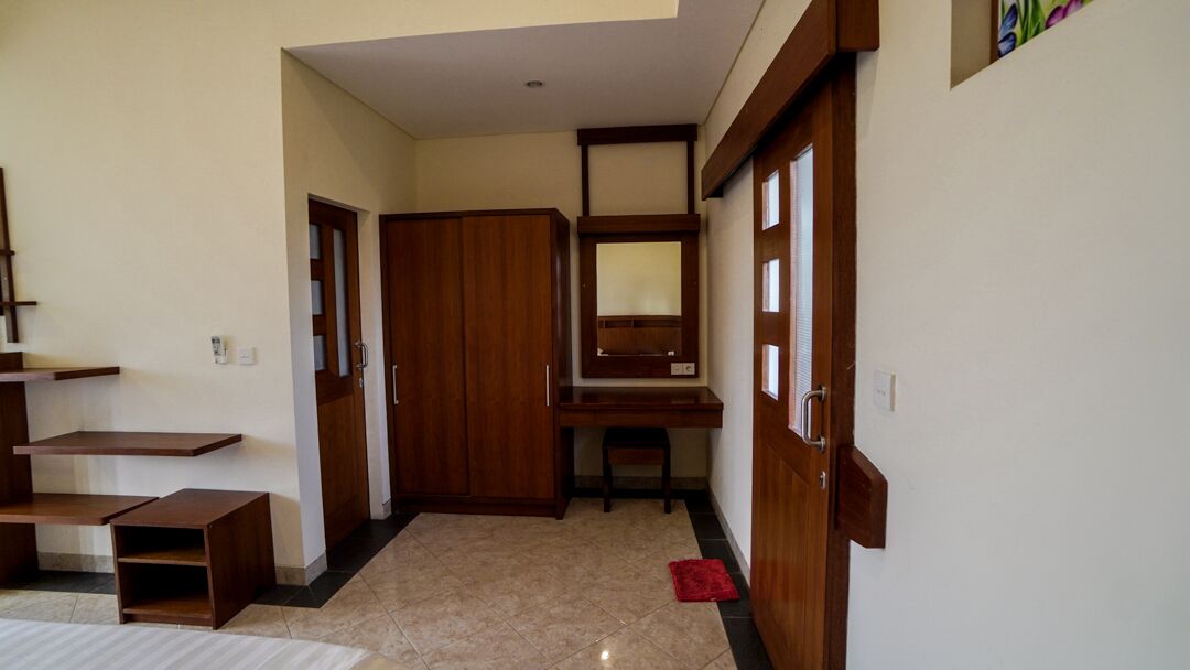 A hallway with a wooden wardrobe, a desk, and a chair.