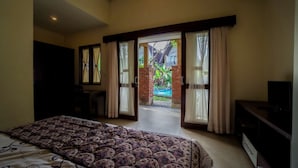 Quarto com cama, televisão e porta de correr para varanda com piscina.