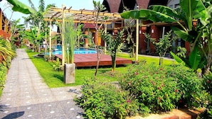 Um resort com piscina, vegetação exuberante e acomodações em bangalôs.