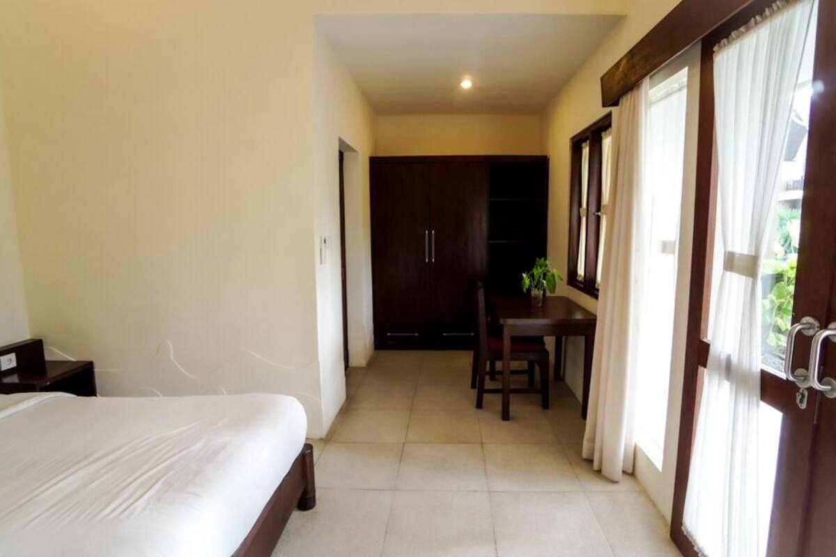A hotel room with a bed, a desk, a chair, and a wardrobe.