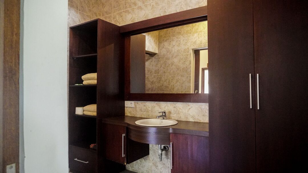 A bathroom with a dark wooden vanity, a sink, and a mirror.