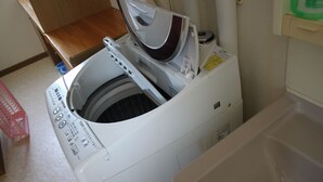 Een voorlader wasmachine in een wasserijruimte met een houten aanrecht en een plastic bak.
