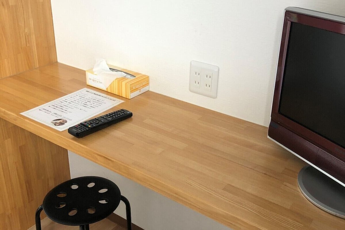 A wooden desk with a remote control, a tissue box, and a monitor.