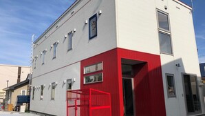 Een modern gebouw met een witte gevel en een rode accentmuur.