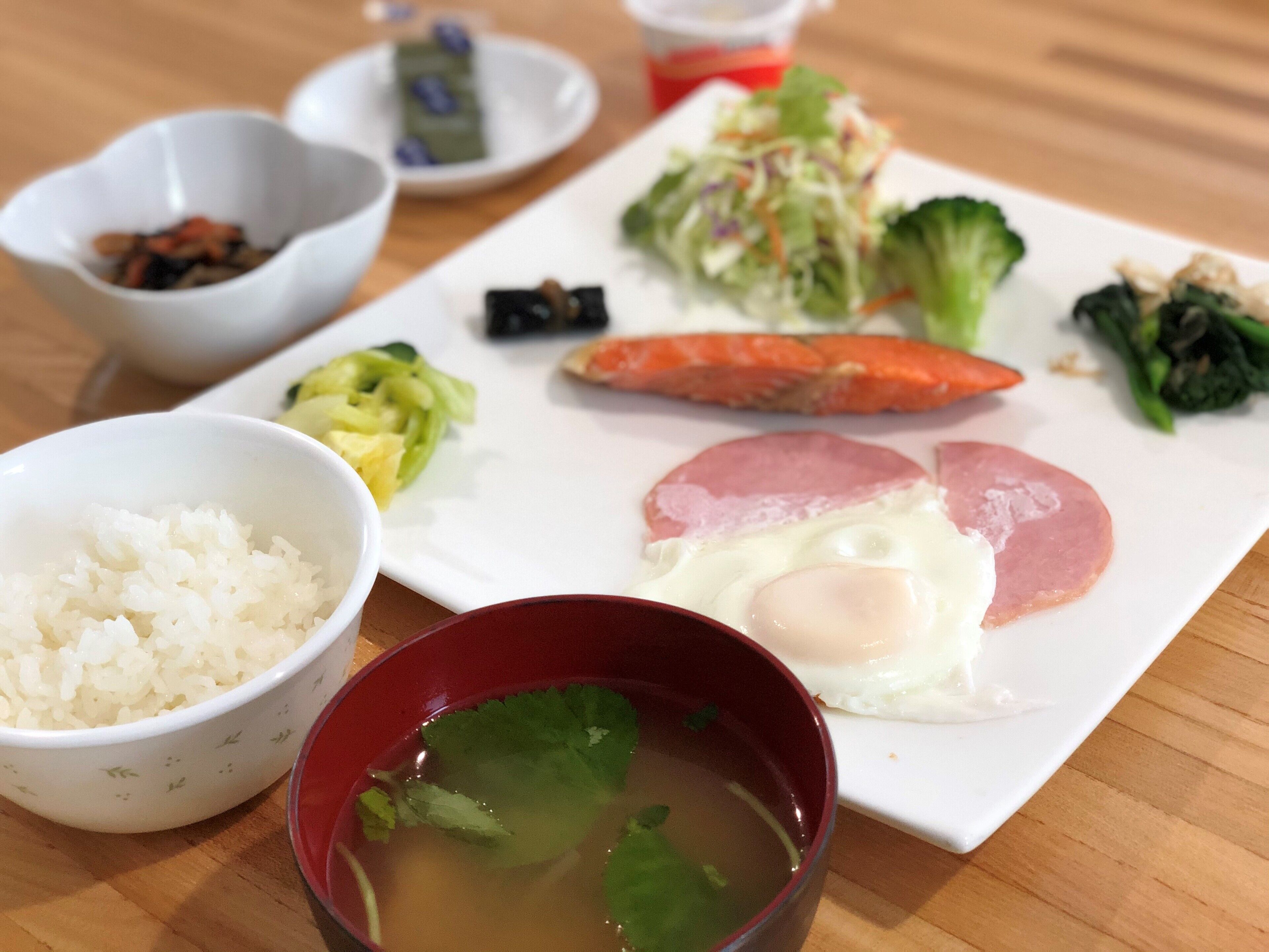 A meal with rice, soup, and various vegetables on a wooden table.