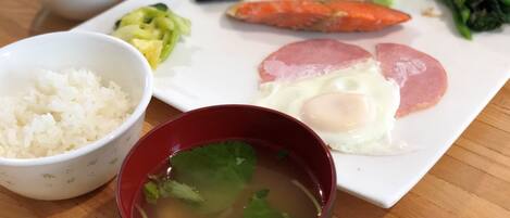 A meal with rice, soup, and various vegetables on a wooden table.