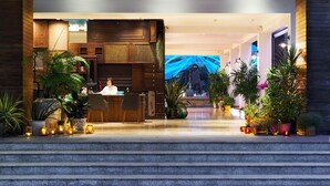 A modern hotel lobby with a reception desk, seating area, and a large digital screen displaying an image. - Loligo Resort Hua Hin (Hua Hin)