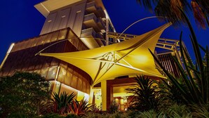 A modern building with a unique architectural design, featuring a prominent overhanging structure and a well-lit entrance area. - Loligo Resort Hua Hin (Hua Hin)