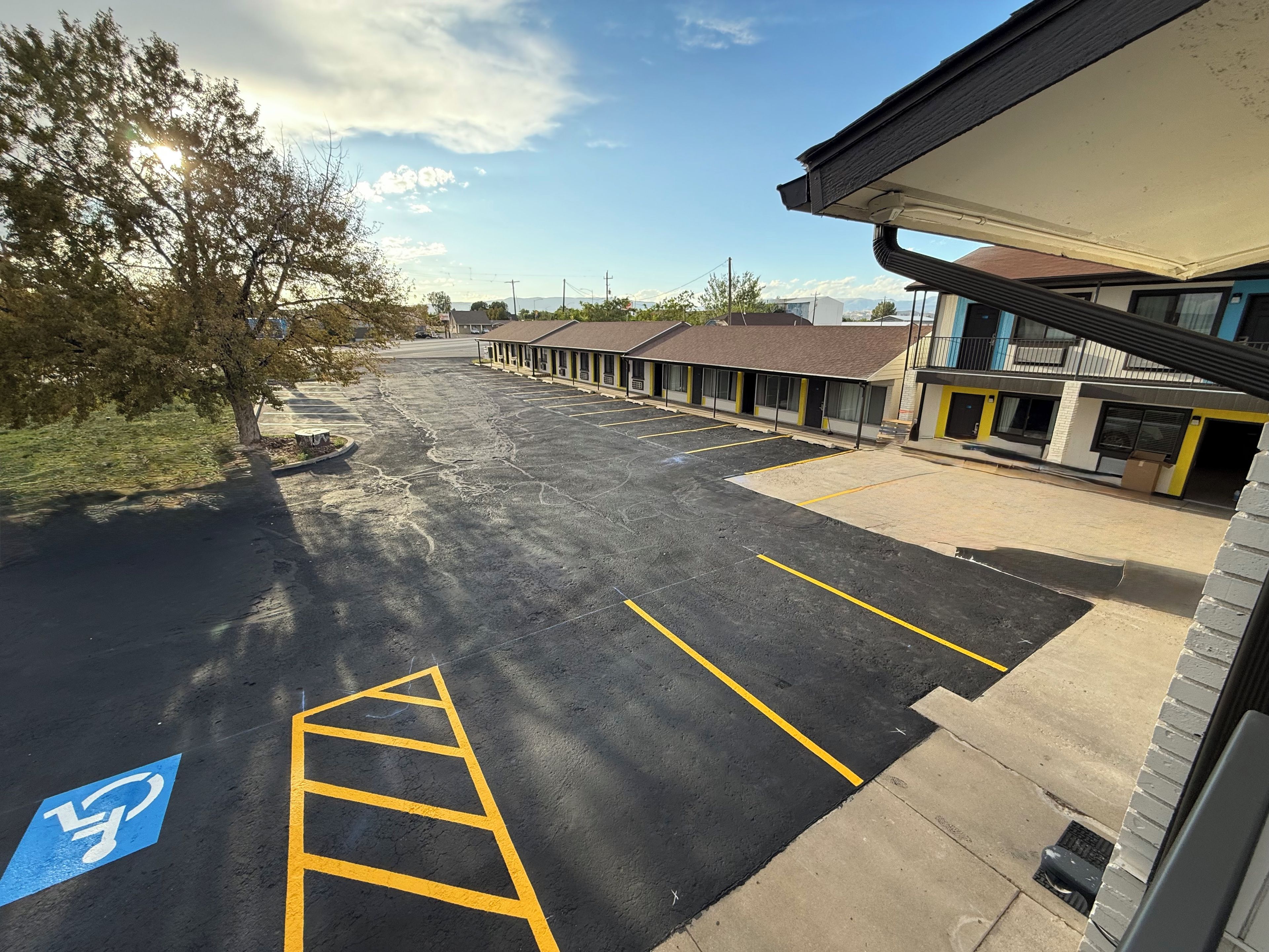 Un parking avec des places réservées aux personnes handicapées et un bâtiment doté d’un toit plat.