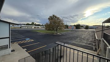 A parking lot with marked spaces, a building with a flat roof, and a tree in the center.