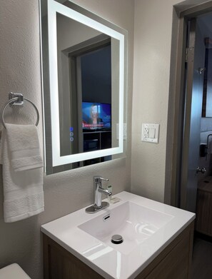 Une salle de bain avec un lavabo blanc, un miroir et un porte-serviettes.