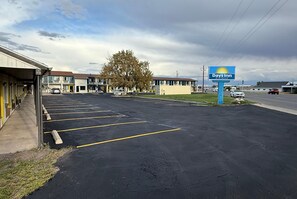A Days Inn motel with a parking lot, a large tree, and a road in the background.